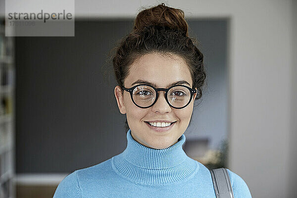 Lächelnde schöne junge Frau mit Brille zu Hause