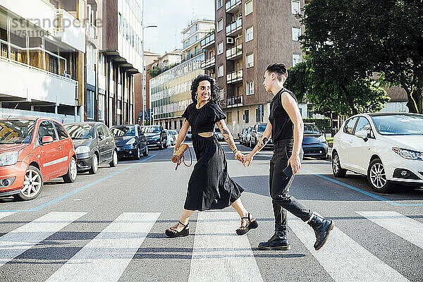 Lächelndes lesbisches Paar überquert die Straße in der Stadt