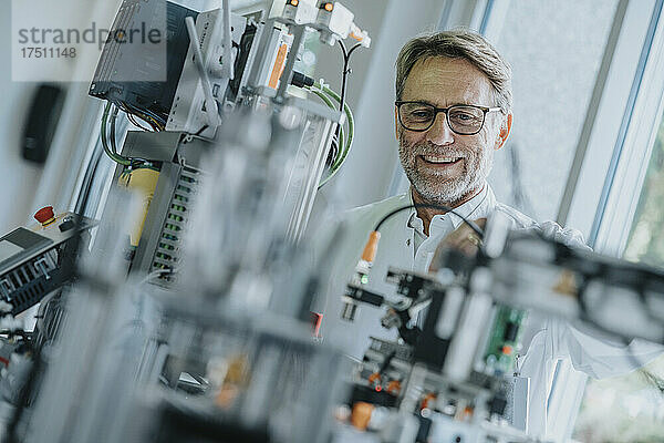 Lächelnder männlicher Ingenieur  der Geräte im Labor untersucht