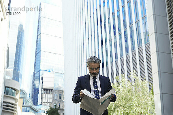 Unternehmer liest Zeitung außerhalb des Büros in der Stadt