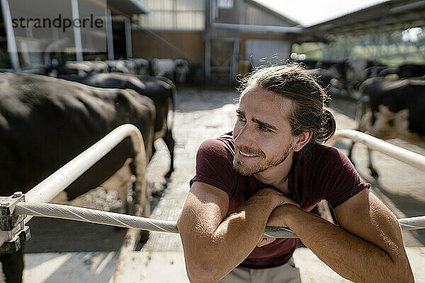 Lächelnder junger Bauer im Kuhstall auf einem Bauernhof