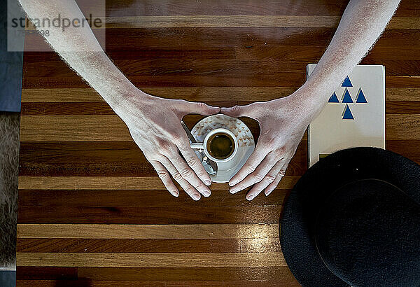 Hände eines Albino-Mannes  der eine Tasse Kaffee hält