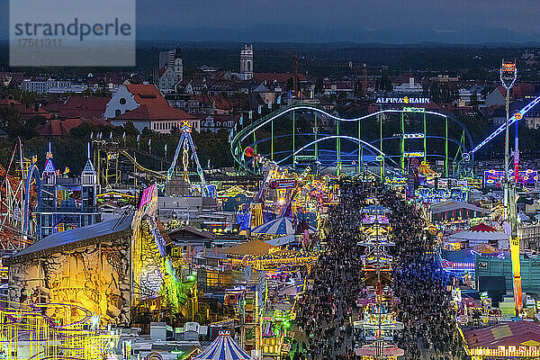 Deutschland  Bayern  München  Drohnenaufnahme von Menschenmassen  die in der Abenddämmerung das Oktoberfest in einem riesigen Vergnügungspark feiern