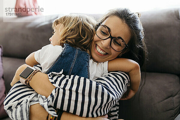 Nahaufnahme einer glücklichen Mutter  die ihre Tochter umarmt  während sie zu Hause auf dem Sofa sitzt