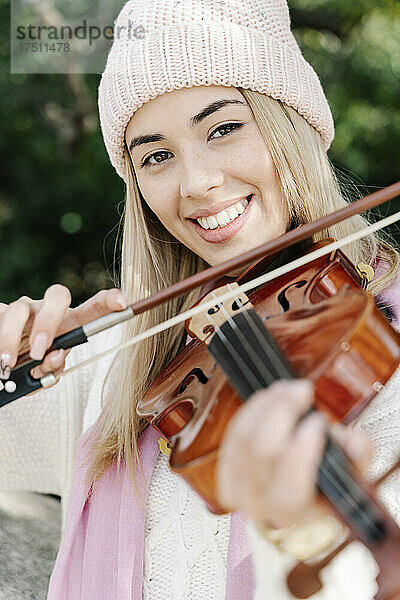 Blonde junge Frau spielt Geige in der Stadt