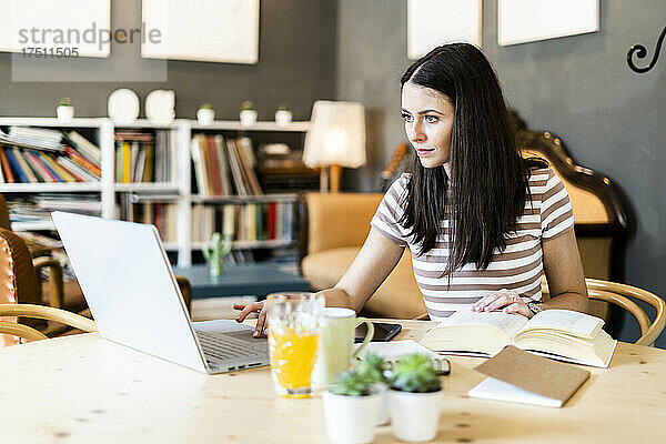 Schöne Frau benutzt Laptop beim Lernen im Café