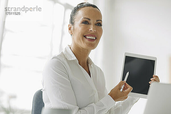 Nahaufnahme eines lächelnden Unternehmers mit digitalem Tablet  der im Heimbüro wegschaut