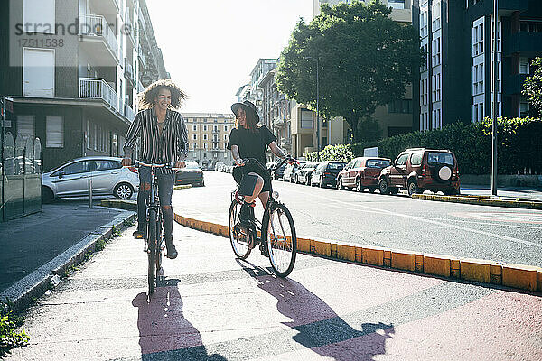 Glückliches Paar  das an sonnigen Tagen auf der Straße in der Stadt Fahrrad fährt