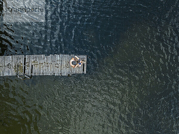 Luftaufnahme eines Mannes und einer Frau  die zusammen am Rande eines Stegs am Seeufer stehen