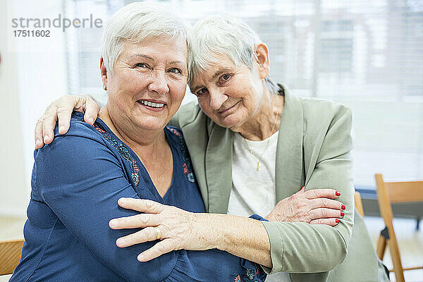 Zwei ältere Frauen umarmen sich im Altersheim