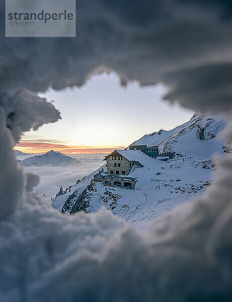 Abgeschiedene Berghütte durch ein Loch im Schnee gesehen