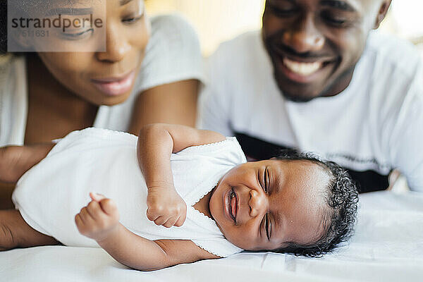 Nahaufnahme lächelnder Eltern  die ihre neugeborene Tochter betrachten  die im Bett schläft