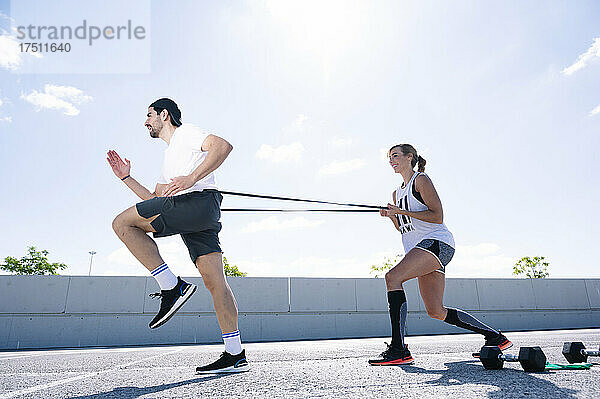 Paar trainiert an sonnigen Tagen mit Riemen auf der Straße gegen den Himmel