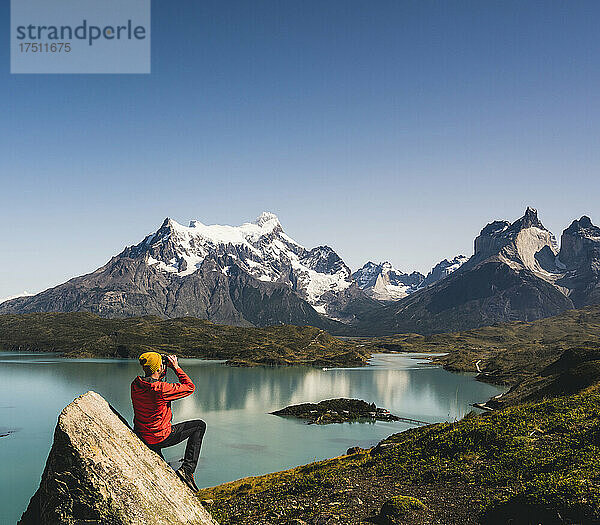 Mann blickt durch ein Fernglas auf den Lake Pehoe im Nationalpark Torres Del Paine  Chile  Patagonien  Südamerika