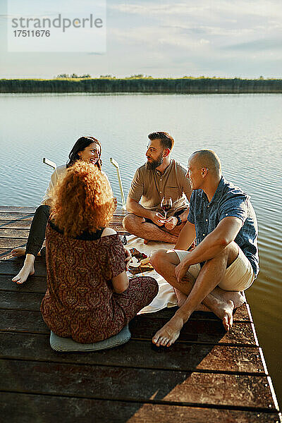 Freunde beim Picknick am Steg an einem See