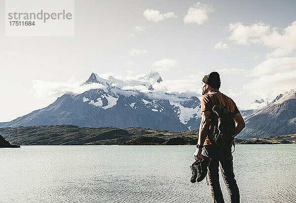 Mann mit Schuhen mit Blick auf den Pehoe-See im Nationalpark Torres Del Paine  Chile  Patagonien  Südamerika