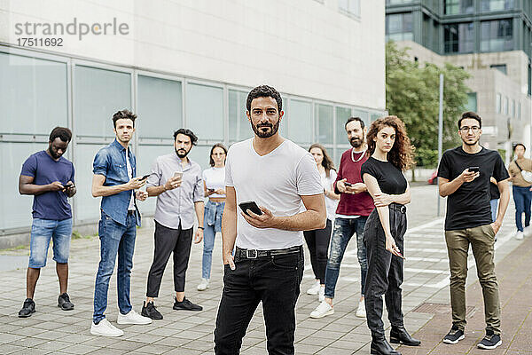 Gruppe von Freunden  die Smartphones benutzen und auf dem Fußweg in der Stadt stehen