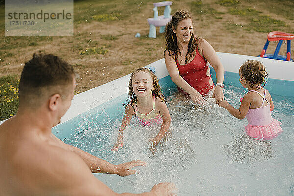Glückliche Familie in einem aufblasbaren Swimmingpool im Garten