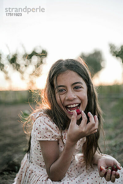 Glückliches Mädchen  das Erdbeeren auf dem Bauernhof isst