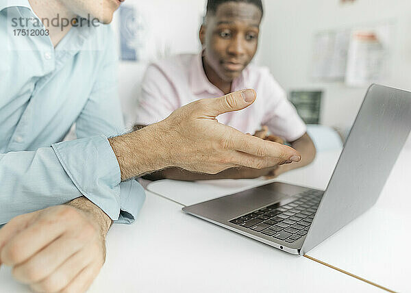 Kollegen arbeiten am Laptop über dem Tisch  während sie im Büro sitzen