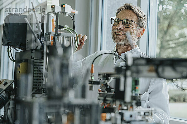 Lächelnder männlicher Techniker untersucht Maschinen im Labor