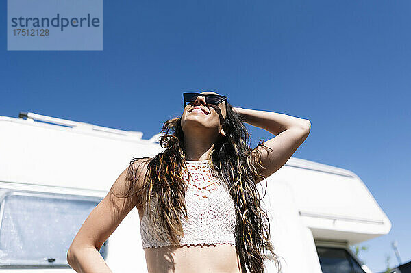 Junge Frau mit Sonnenbrille vor Wohnmobil