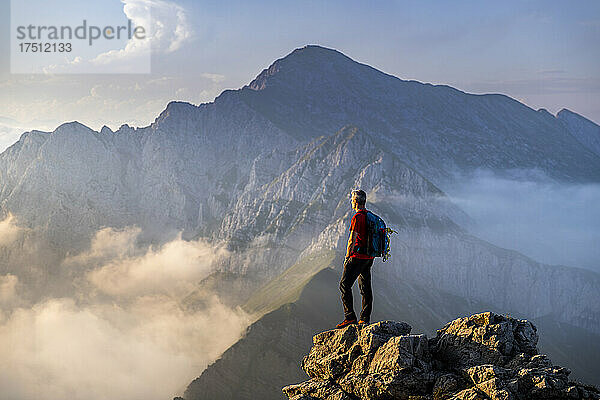 Mann steht auf dem Gipfel eines Berges in den Bergamasker Alpen  Italien