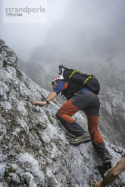 Reifer männlicher Wanderer klettert bei nebligem Wetter auf den Berg  Bergamasker Alpen  Italien