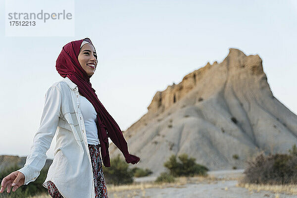 Lächelnde junge Touristin mit Hijab in Wüstenlandschaft