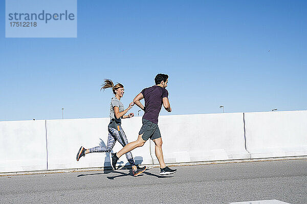 Paar läuft an sonnigen Tagen auf der Straße gegen den klaren blauen Himmel in der Stadt