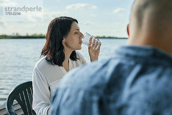 Junge Frau trinkt ein Glas Wasser an einem See