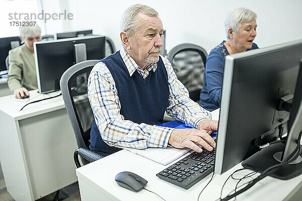 Aktive Senioren besuchen einen Computerkurs und arbeiten am PC
