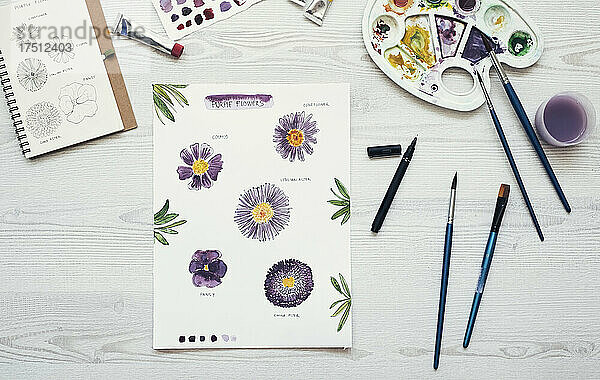 Watercolor painting of purple flowers on the desk  top view