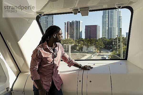 Junger Mann mit Dreadlocks schaut durch das Fenster  während er im Zug steht  Miami  Florida  USA