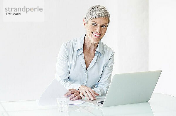 Porträt einer lächelnden reifen Geschäftsfrau  die am Laptop arbeitet