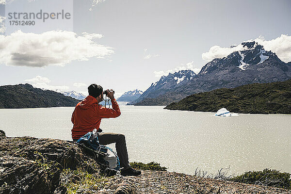 Mann blickt mit einem Fernglas auf den Grey-Gletscher im Nationalpark Torres Del Paine  Patagonien  Chile  Südamerika