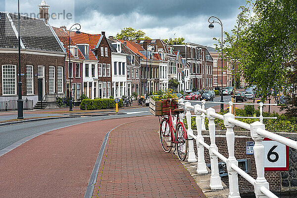 Niederlande  Nordholland  Haarlem  Fahrrad geparkt am Geländer der Kanalbrücke mit Häusern entlang der Hooimarkt-Straße im Hintergrund