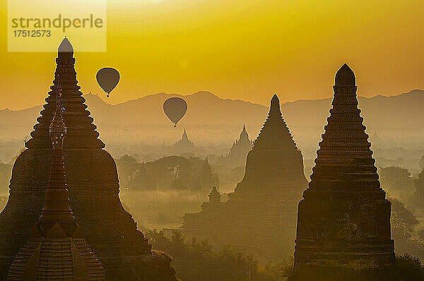 Myanmar  Mandalay-Region  Bagan  Heißluftballons fliegen in der nebligen Dämmerung über antike Stupas