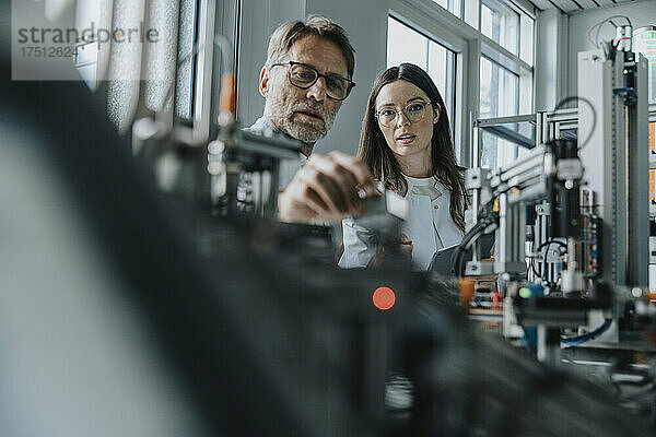 Männlicher Wissenschaftler und junge Frau untersuchen Maschinen im Labor