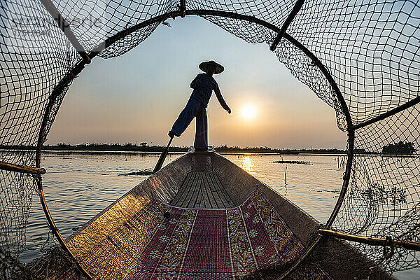 Myanmar  Shan-Staat  Silhouette eines traditionellen Intha-Fischers auf einem Boot auf dem Inle-See bei Sonnenuntergang