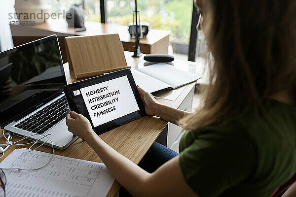 Nahaufnahme einer Geschäftsfrau  die im Heimbüro ein digitales Tablet auf dem Schreibtisch nutzt