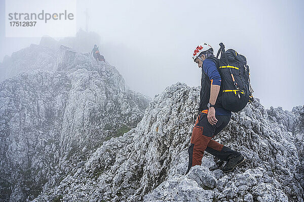 Reife Männer wandern bei nebligem Wetter auf felsigen Bergen gegen den Himmel  Bergamasker Alpen  Italien