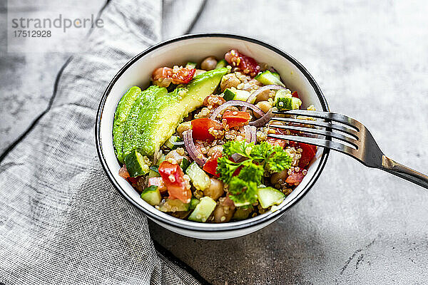 Schüssel mit vegetarischem Quinoa-Salat mit Kichererbsen  Avocado  Gurke  Tomate  Zwiebel und Petersilie