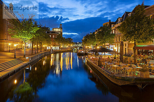 Niederlande  Südholland  Leiden  Straßencafé und beleuchteter Nieuwe-Rijn-Kanal in der Abenddämmerung