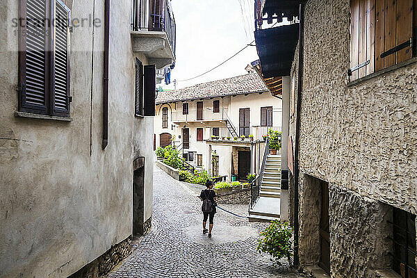 Italien  Piemont  Touristin steht mitten in einer gepflasterten Gasse in einem alten ländlichen Dorf