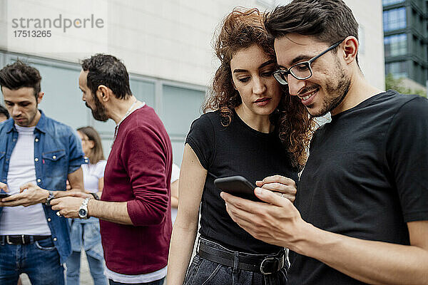 Freunde nutzen Smartphones  während sie in der Stadt herumhängen