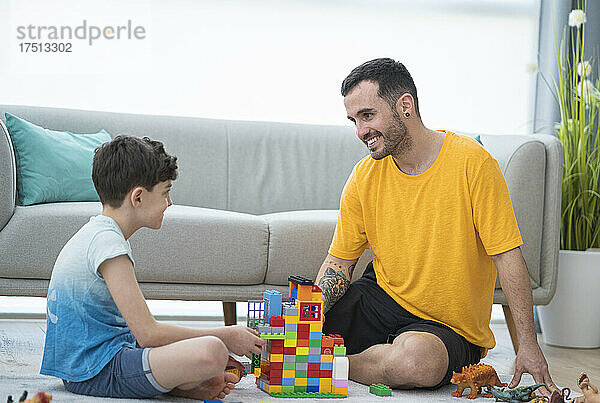 Lächelnder Vater spielt mit Sohn im Wohnzimmer