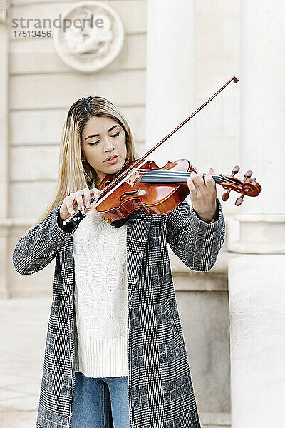 Blonde junge Frau spielt Geige in der Stadt