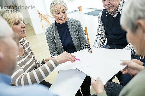 Eine Gruppe von Senioren besucht eine Therapiegruppe im Altersheim und verwendet dabei Blätter