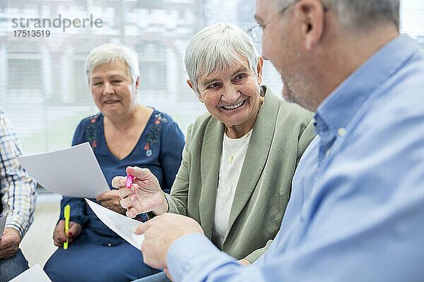 Senioren in der Therapiegruppe im Altersheim schreiben Notizen auf Papierbögen